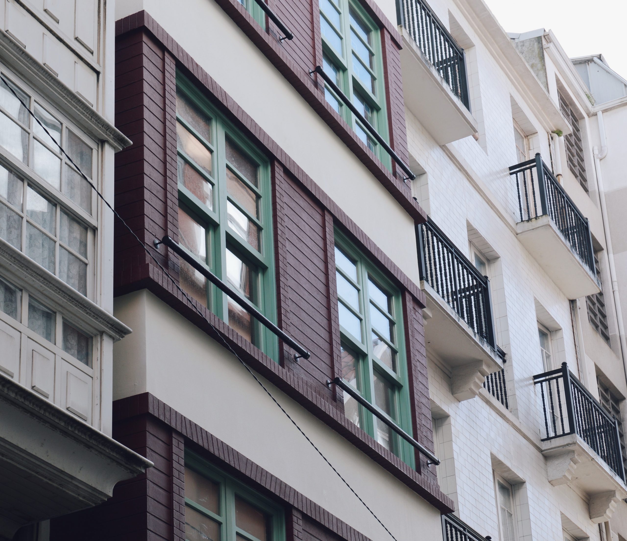 Balcón con ventanas verdes - Reforma de edificio en Orzán